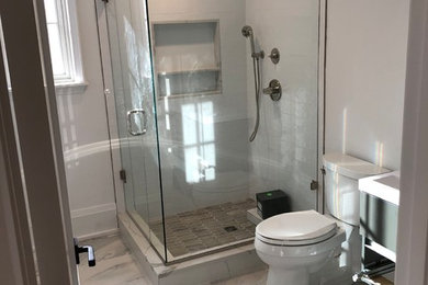 Mittelgroßes Badezimmer mit Eckdusche, Wandtoilette mit Spülkasten, weißen Fliesen, Keramikfliesen, Quarzit-Waschtisch, Falttür-Duschabtrennung und weißer Waschtischplatte in New York