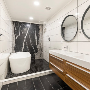 Inspiration for a large contemporary master black and white tile black floor and double-sink bathroom remodel in Phoenix with flat-panel cabinets, medium tone wood cabinets, an integrated sink, white countertops and a floating vanity