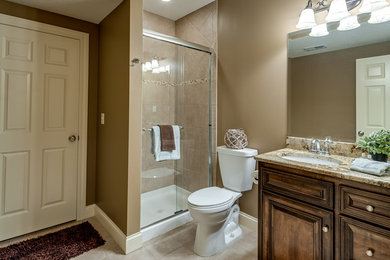 Cette image montre une salle d'eau traditionnelle en bois brun de taille moyenne avec un placard en trompe-l'oeil, une douche d'angle, WC à poser, un carrelage beige, des carreaux de porcelaine, un mur marron, un sol en carrelage de céramique, un lavabo encastré et un plan de toilette en granite.