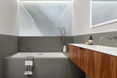 Bathroom - mid-sized contemporary master stone slab limestone floor and gray floor bathroom idea in San Francisco with furniture-like cabinets, medium tone wood cabinets, a wall-mount toilet, gray walls, an integrated sink and solid surface countertops