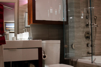 Idéer för små funkis badrum med dusch, med släta luckor, skåp i mellenmörkt trä, ett badkar i en alkov, en dusch/badkar-kombination, en toalettstol med hel cisternkåpa, grå kakel, porslinskakel, grå väggar, klinkergolv i porslin, ett integrerad handfat och bänkskiva i akrylsten