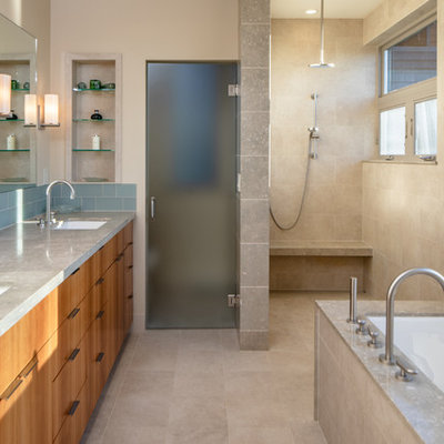 Example of a mid-sized trendy master beige tile and porcelain tile porcelain tile and beige floor bathroom design in Seattle with flat-panel cabinets, brown cabinets, an undermount tub, a one-piece toilet, beige walls, a drop-in sink, granite countertops and gray countertops