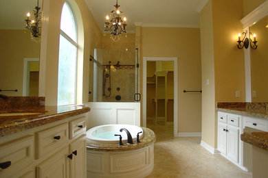 Example of a large classic master limestone floor bathroom design in Houston with white cabinets, granite countertops and beige walls