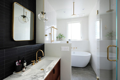 Bathroom - mid-sized eclectic master black and white tile and ceramic tile concrete floor and gray floor bathroom idea in San Francisco with furniture-like cabinets, medium tone wood cabinets, a one-piece toilet, white walls, an undermount sink, marble countertops and a hinged shower door