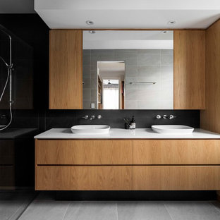 Large contemporary master bathroom in Brisbane with medium wood cabinets, black tile, white benchtops, flat-panel cabinets, a curbless shower, black walls, a vessel sink and grey floor.