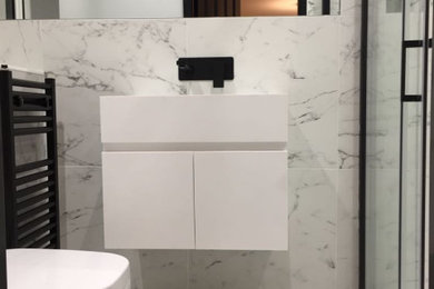 Small contemporary ensuite bathroom in West Midlands with flat-panel cabinets, white cabinets, a one-piece toilet, grey tiles, porcelain tiles, grey walls, porcelain flooring, a wall-mounted sink, grey floors, a sliding door, a single sink and a floating vanity unit.