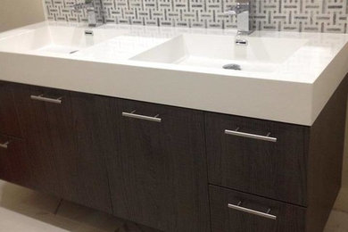 Example of a mid-sized transitional master ceramic tile marble floor and gray floor bathroom design in Los Angeles with flat-panel cabinets, dark wood cabinets, solid surface countertops and an integrated sink