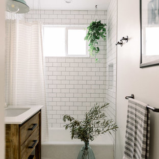Kleines Country Kinderbad mit flächenbündigen Schrankfronten, hellbraunen Holzschränken, Eckbadewanne, Duschnische, Wandtoilette mit Spülkasten, weißen Fliesen, Metrofliesen, weißer Wandfarbe, Porzellan-Bodenfliesen, Waschtischkonsole, Quarzwerkstein-Waschtisch, schwarzem Boden, Duschvorhang-Duschabtrennung und weißer Waschtischplatte in San Diego