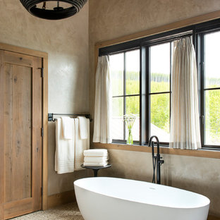 Modelo de cuarto de baño principal, rural, de tamaño medio, con bañera exenta, paredes beige, suelo con mosaicos de baldosas y suelo beige