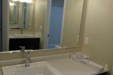Example of a large minimalist kids' vinyl floor bathroom design in Milwaukee with flat-panel cabinets, dark wood cabinets, a two-piece toilet, beige walls, a drop-in sink and laminate countertops