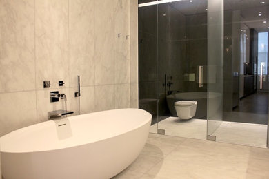 Ejemplo de cuarto de baño principal moderno con bañera exenta, sanitario de pared, paredes negras y suelo de mármol