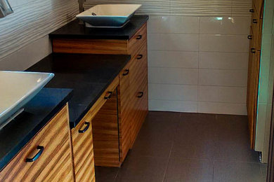 Example of a mid-sized minimalist master white tile and porcelain tile porcelain tile and gray floor bathroom design with flat-panel cabinets, dark wood cabinets, white walls, a vessel sink and solid surface countertops