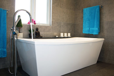 This is an example of a large contemporary ensuite bathroom in Montreal with a submerged sink, white cabinets, granite worktops, a freestanding bath, a walk-in shower, a two-piece toilet, grey tiles, porcelain tiles, white walls and porcelain flooring.