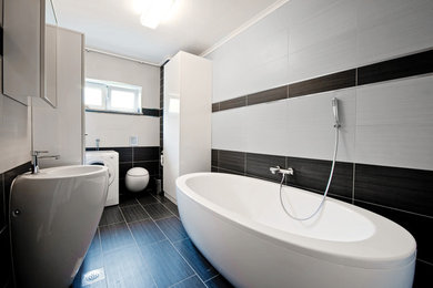 トロントにある低価格の小さなモダンスタイルのおしゃれな浴室 (ペデスタルシンク、置き型浴槽、シャワー付き浴槽	、一体型トイレ	、青いタイル、磁器タイル、白い壁、磁器タイルの床) の写真