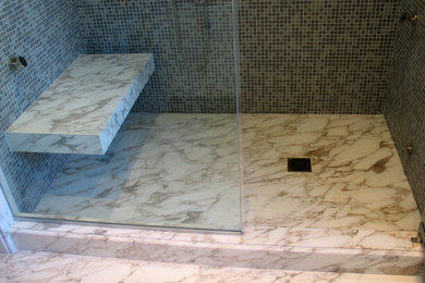 Example of a mid-sized trendy multicolored tile and glass tile marble floor and white floor alcove shower design in New York with multicolored walls, a one-piece toilet and a hinged shower door