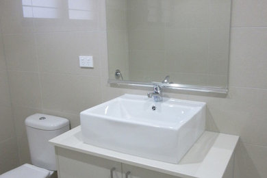 Diseño de cuarto de baño minimalista con puertas de armario blancas, baldosas y/o azulejos beige, baldosas y/o azulejos de cerámica, lavabo sobreencimera y encimera de granito
