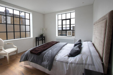 Photo of a contemporary bedroom in London with white walls and dark hardwood flooring.