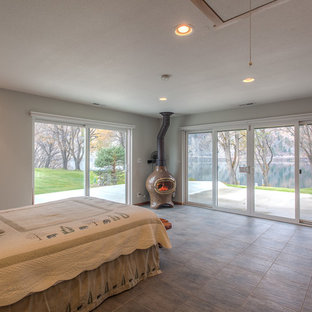 Imagen de habitación de invitados costera, de tamaño medio, con paredes grises, suelo de baldosas de cerámica, estufa de leña y suelo gris