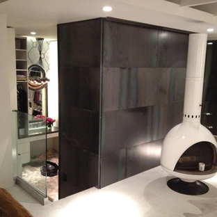 Ejemplo de dormitorio moderno con suelo de cemento, estufa de leña y marco de chimenea de metal
