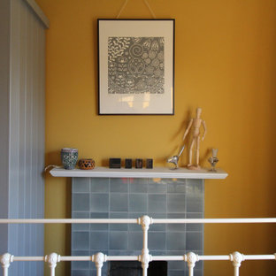 Imagen de habitación de invitados escandinava, pequeña, con paredes amarillas, suelo de madera oscura, chimenea tradicional y marco de chimenea de baldosas y/o azulejos