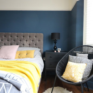 Modelo de dormitorio principal, bohemio, de tamaño medio, con paredes azules, suelo de madera oscura, chimenea tradicional y marco de chimenea de baldosas y/o azulejos
