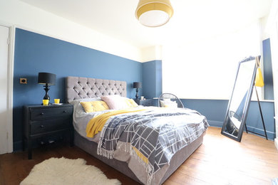 ケンブリッジシャーにある中くらいなエクレクティックスタイルのおしゃれな主寝室 (青い壁、濃色無垢フローリング、標準型暖炉、タイルの暖炉まわり)