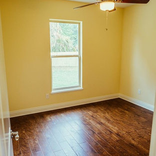 Diseño de habitación de invitados clásica renovada, de tamaño medio, con paredes amarillas, suelo de madera oscura y suelo marrón