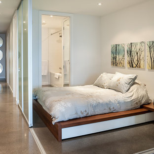 Ispirazione per una camera da letto minimal con pareti bianche e pavimento in cemento