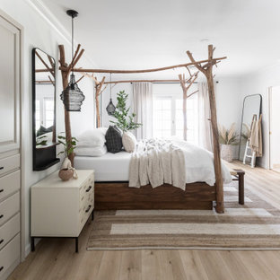 Foto di una camera matrimoniale bohémian di medie dimensioni con pareti bianche, parquet chiaro, camino lineare Ribbon e cornice del camino in intonaco