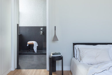 Ejemplo de dormitorio principal minimalista de tamaño medio sin chimenea con paredes blancas, suelo de madera clara y suelo beige