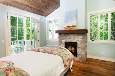 グランドラピッズにある小さなビーチスタイルのおしゃれな主寝室 (緑の壁、無垢フローリング、標準型暖炉、石材の暖炉まわり) のインテリア