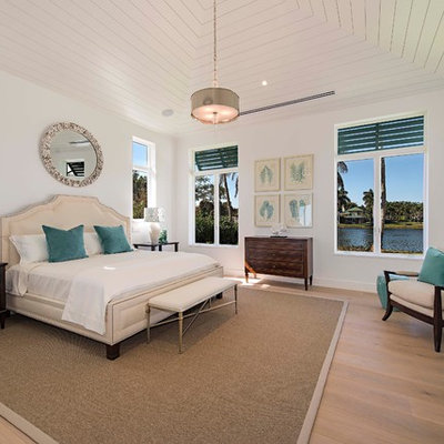 Example of a beach style master light wood floor bedroom design in Miami with white walls