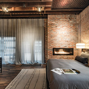 Imagen de dormitorio principal, industrial, con paredes rojas, suelo de madera oscura, chimenea lineal y marco de chimenea de metal