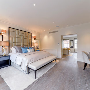 This is an example of a large traditional master bedroom in London with beige walls, medium hardwood flooring and beige floors.