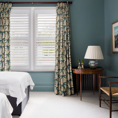 Example of a classic guest carpeted and white floor bedroom design in London with blue walls and a standard fireplace