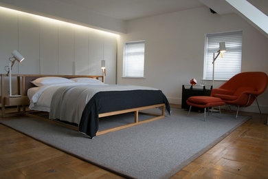 Diseño de dormitorio tipo loft actual de tamaño medio con paredes blancas y suelo de madera en tonos medios