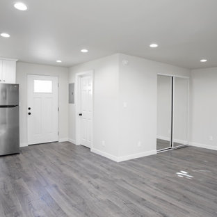 Imagen de dormitorio tipo loft, moderno, de tamaño medio, sin chimenea, con paredes blancas, suelo vinílico y suelo gris
