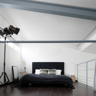 Diseño de dormitorio tipo loft, industrial, con paredes blancas, suelo de madera oscura y suelo marrón