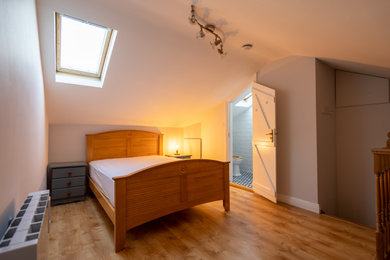 Ejemplo de dormitorio principal clásico de tamaño medio con paredes blancas, suelo de madera en tonos medios y suelo marrón