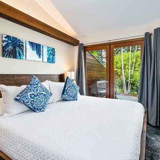Modelo de habitación de invitados tropical, de tamaño medio, con paredes blancas, suelo de pizarra y suelo negro