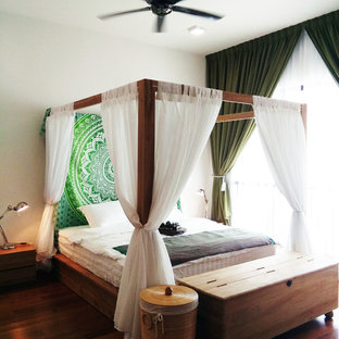 Modelo de dormitorio principal, tropical, de tamaño medio, con paredes blancas, suelo laminado y suelo marrón
