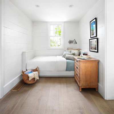 Bedroom - small coastal medium tone wood floor bedroom idea in Other with white walls