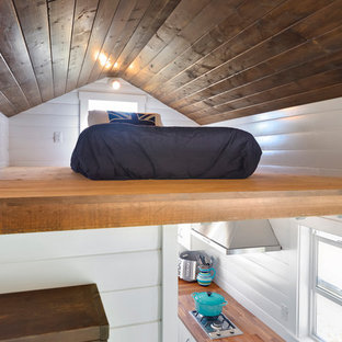 Bild på ett litet maritimt sovloft, med vita väggar och plywoodgolv