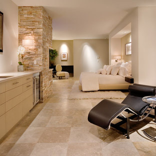 Diseño de dormitorio principal, actual, con paredes beige, suelo de travertino y marco de chimenea de piedra