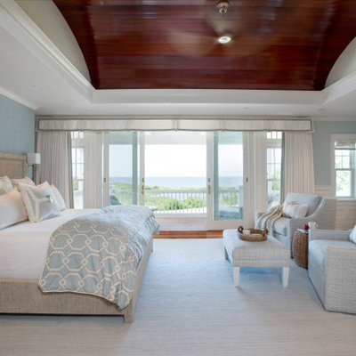 Example of a large beach style master medium tone wood floor and brown floor bedroom design in Boston with blue walls