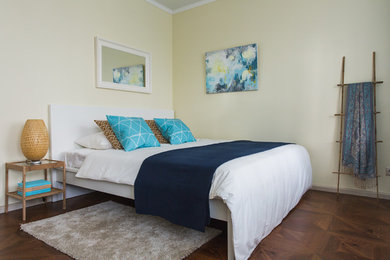Modelo de dormitorio principal nórdico con paredes amarillas y suelo de madera en tonos medios