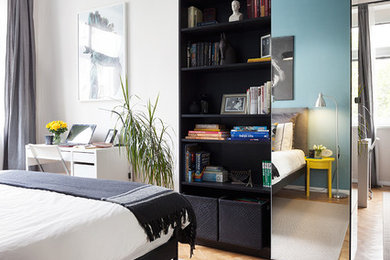 Imagen de dormitorio principal actual de tamaño medio con paredes azules y suelo de madera clara