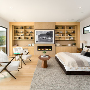 Diseño de dormitorio principal, contemporáneo, grande, con paredes blancas, suelo de madera clara, chimenea lineal, marco de chimenea de metal y suelo beige