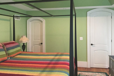 Elegant master medium tone wood floor and brown floor bedroom photo in Other with green walls
