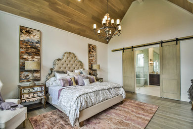 Photo of a large traditional master bedroom in Dallas with white walls and light hardwood flooring.